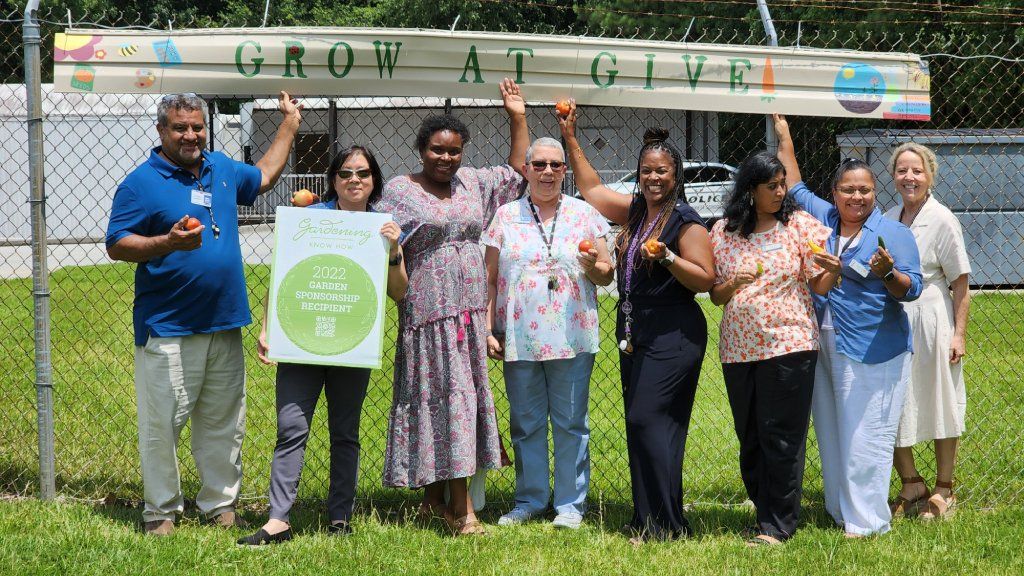 A group of smiling people holding a sign