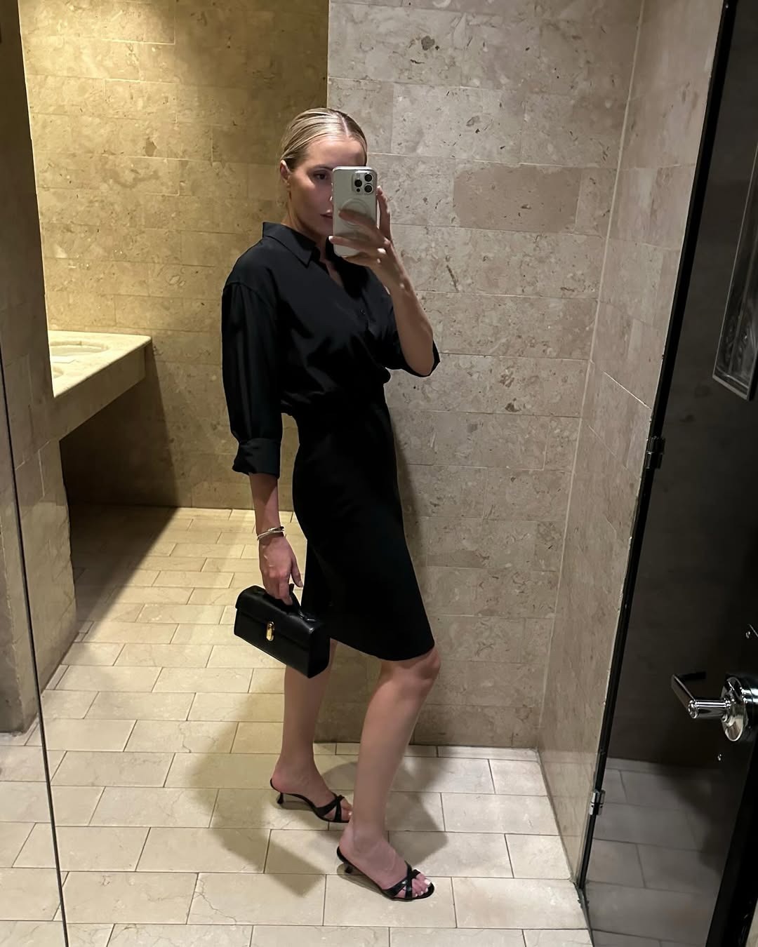 Kristen Nichols wearing a black button-down shirt, black pencil skirt, and black sandals.