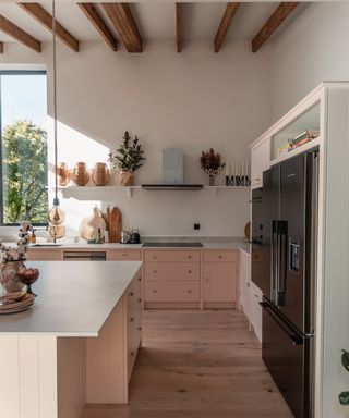 A modern country kitchen with pink drawers and overhead beams