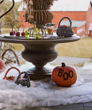 outdoor porch halloween display with round table and faux cobwebs with a pumpkin