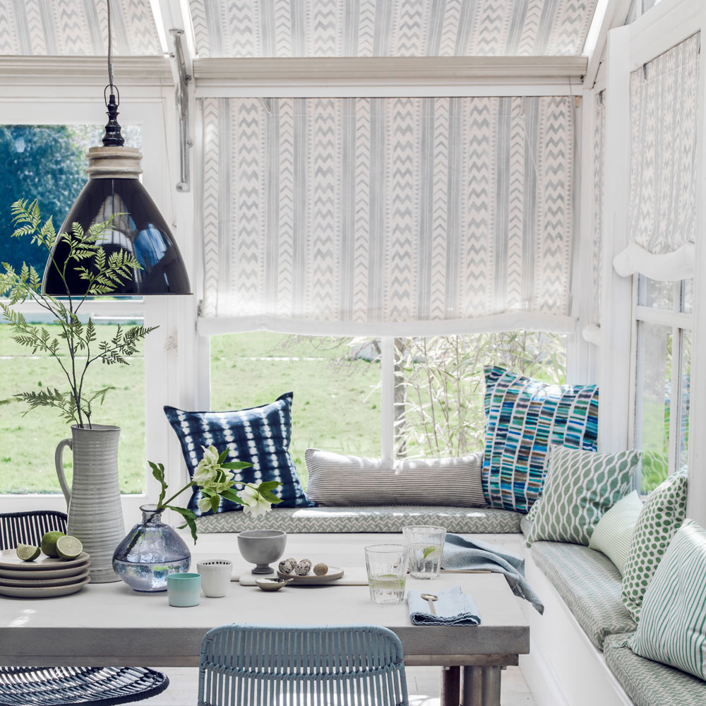 Conservatory with striped blinds and dining table with overhead pendant