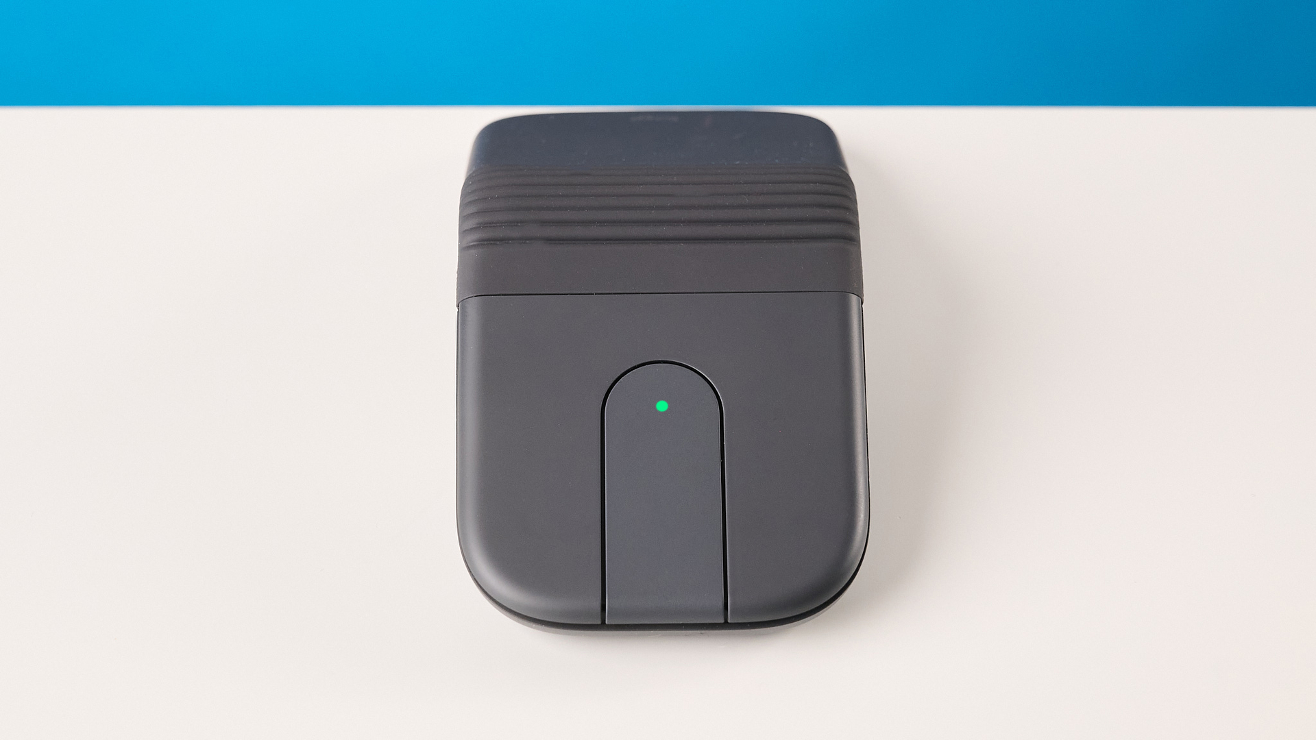 Logitech Mobi Fold mouse in graphite photographed in front of a blue background