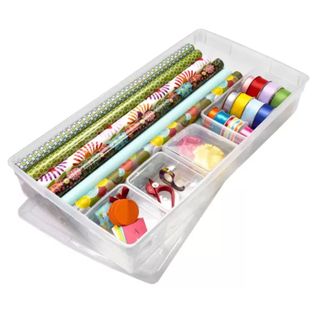 A clear plastic underbed box full of Christmas wrapping supplies