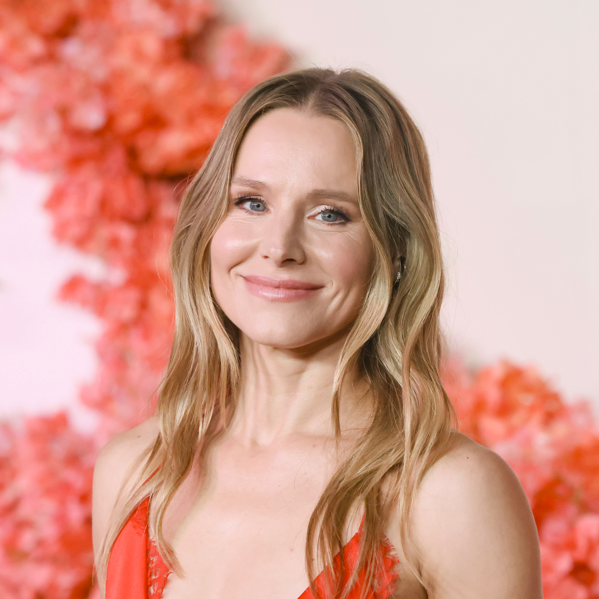Kristen Bell attends the premiere of Netflix's "Nobody Wants This" Season 2 wearing red dress in front of floral display