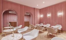 Pink velvet walled room with white arm chairs & tables 