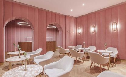 Pink velvet walled room with white arm chairs & tables 