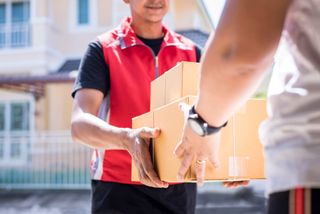 Parcel delivery man of a package through a service and customer hand accepting a delivery of boxes from delivery man