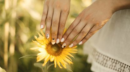 Beautiful summer manicure on a sunflower background. Summer vacation concept, recreation in the countryside, nature beauty, gardening, nailcare. Sunflower nail designs