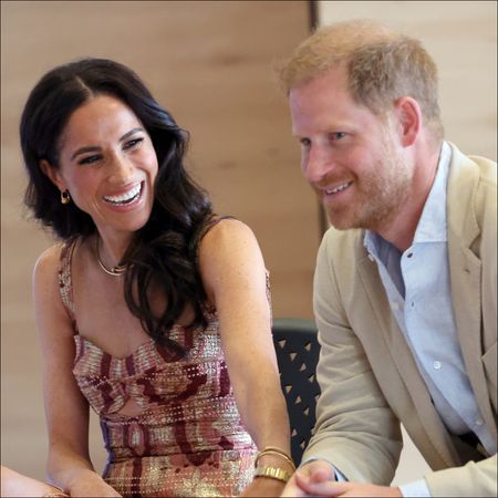 Meghan Markle laughs while wearing a pretty pink dress while looking at Prince Harry during their visit to Bogota, Colombia on August 15, 2024 