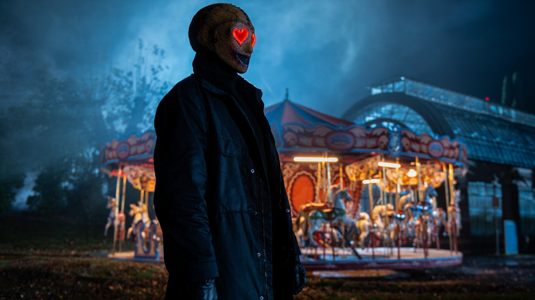 The Heart Eyes killer stands in front of a carousel