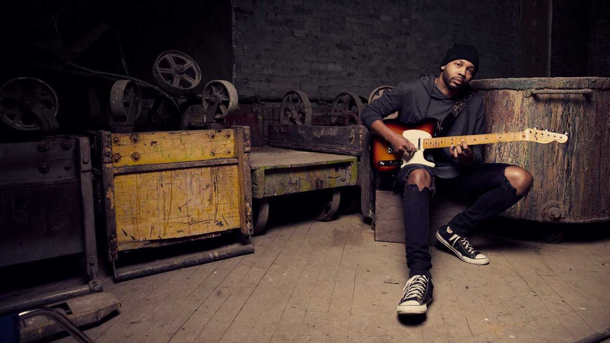 Ayron Jones sitting on a box in an old machinery shed 