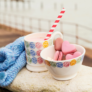 Swizzles bowl and mug on a rock, The bowl is filled with heart shaped macaroons.