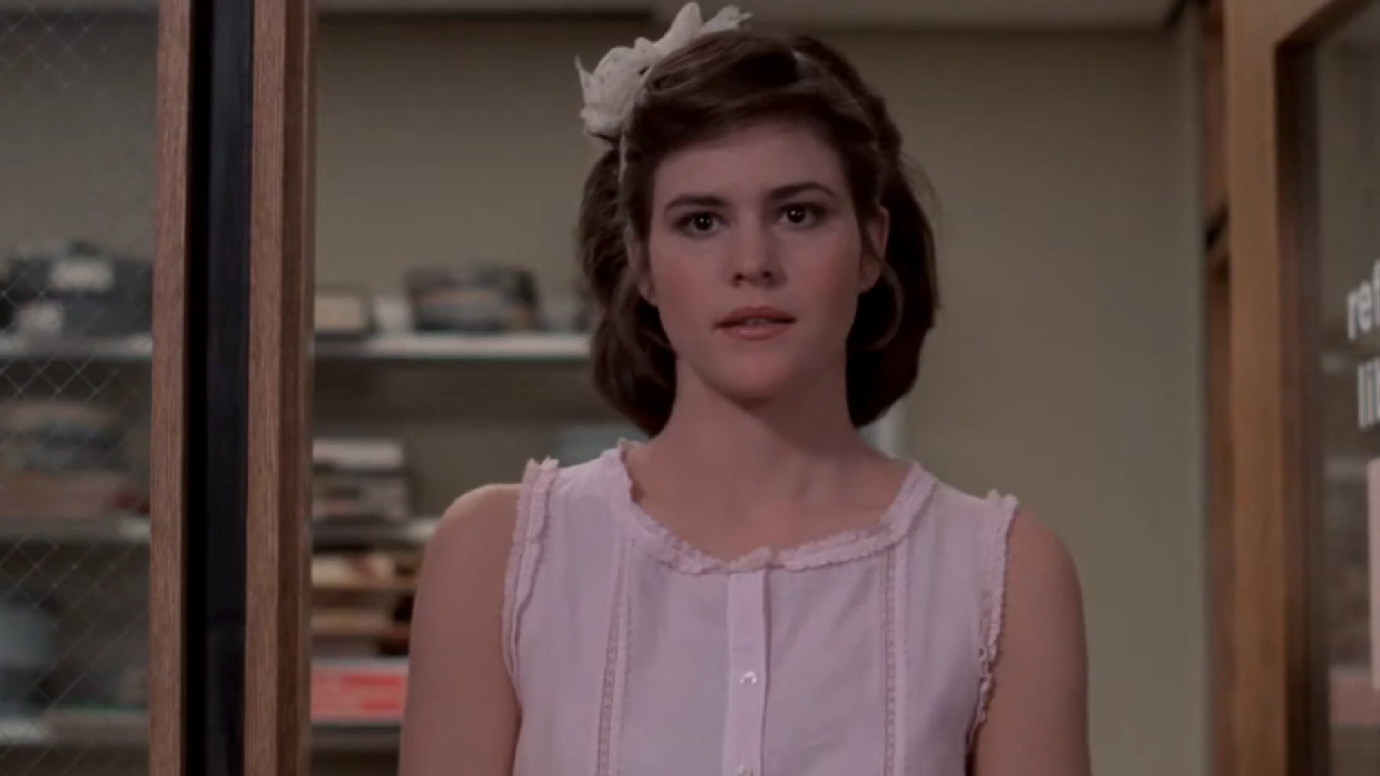 Ally Sheedy in a pink dress with a white bow in her hair in The Breakfast Club