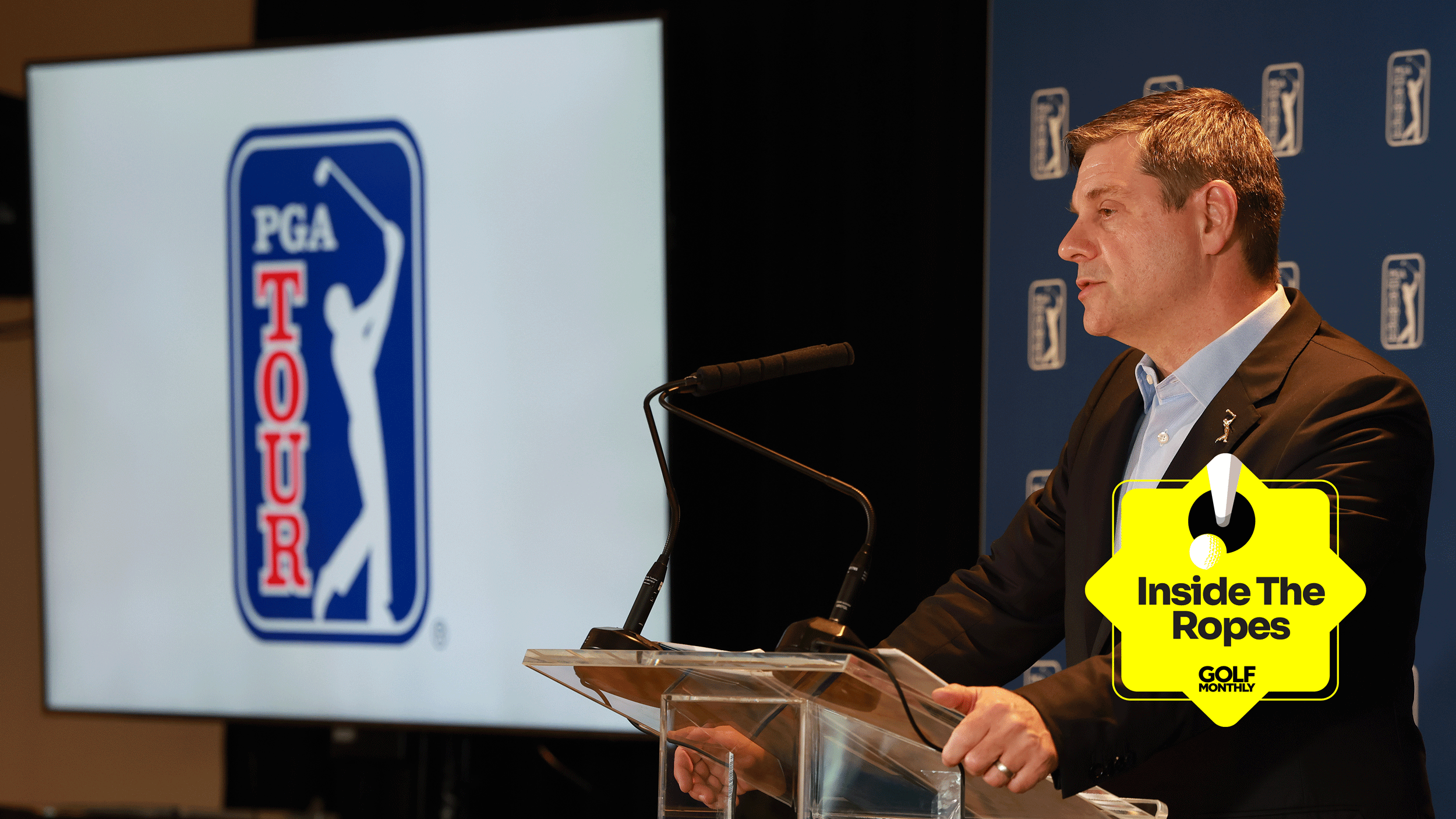 Brian Rolapp addresses the media at TPC River Highlands with a screen displaying the PGA Tour logo on the left