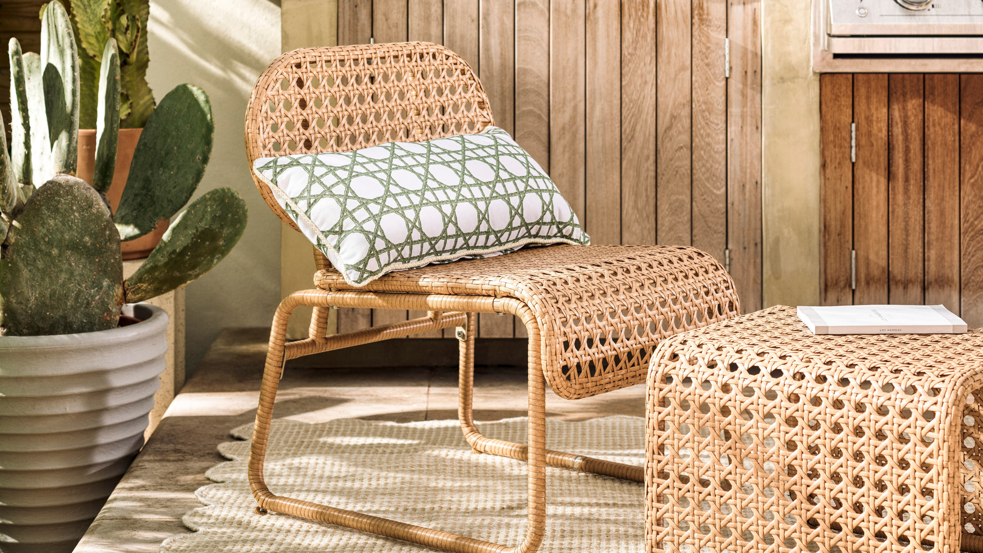 Habitat global accent chair and footstool on cream scalloped rug on patio. Behind is a silver bbq and wooden sidebaord. A cactus is the left of the chair.