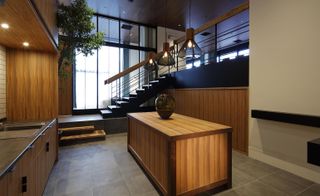wooden themed kitchen with wooden island and stairs up to the next level in the background