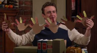 Screenshot of Jason Segel holding up turkey hand decorations in How I Met Your Mother.