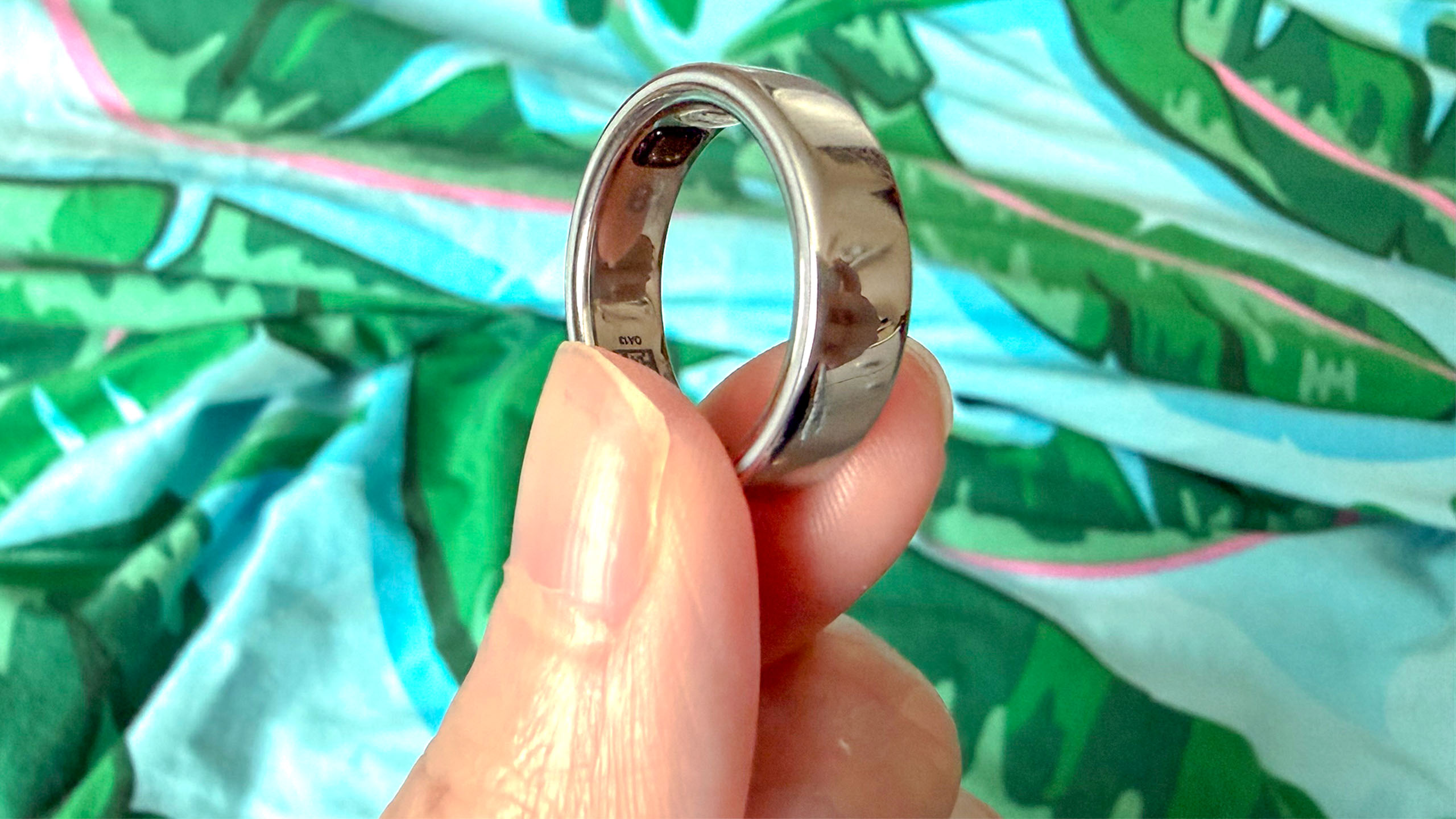 A close up of a hand holding the Oura Ring 5