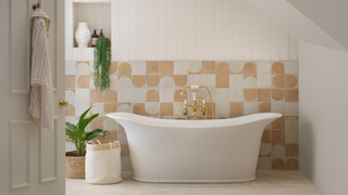 Bathroom with white freestanding bathtub with beige and white tiles behind it on the lower half of wall and white panels above it