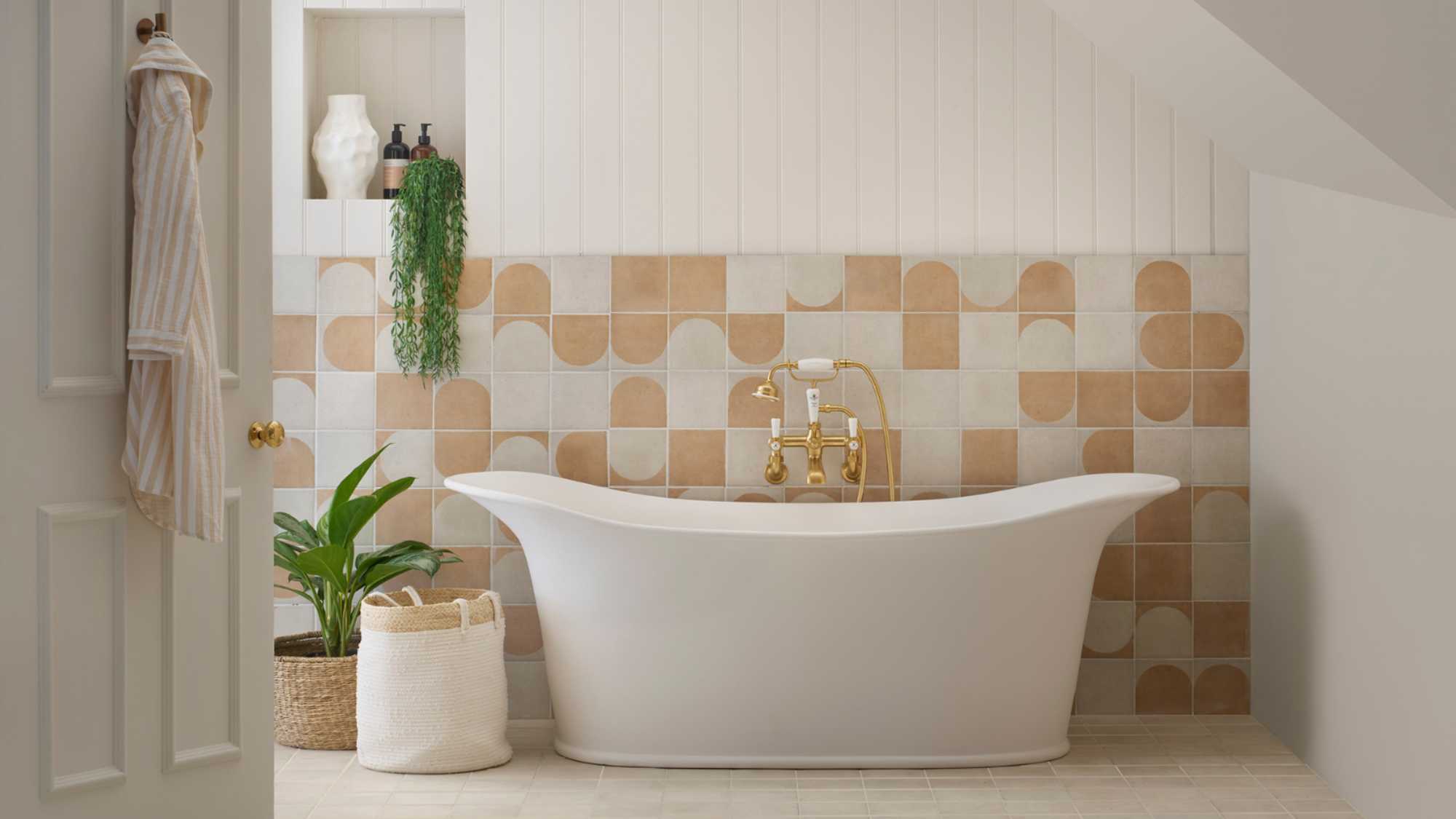 Bathroom with white freestanding bathtub with beige and white tiles behind it on the lower half of wall and white panels above it