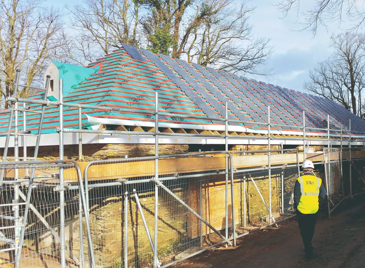 A slate roof on a stone barn under construction