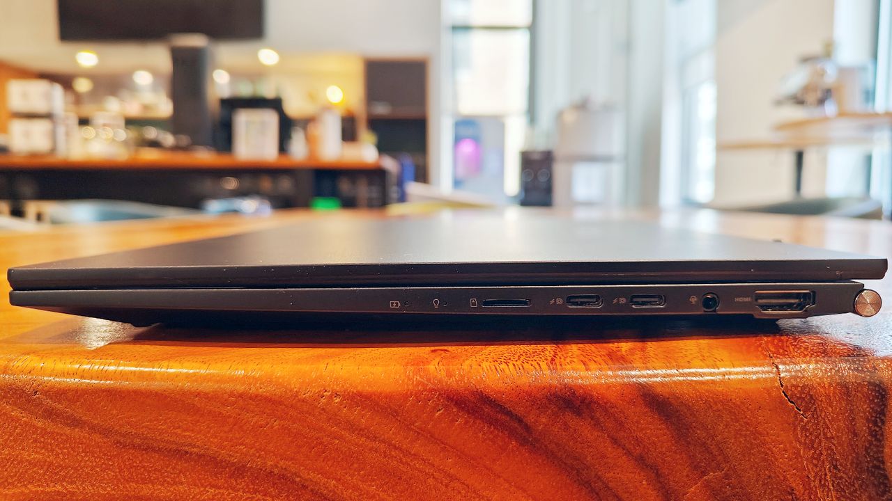 Asus Zenbook 14 OLED UM3402Y closed on a wooden desk showing the ports on its right side.