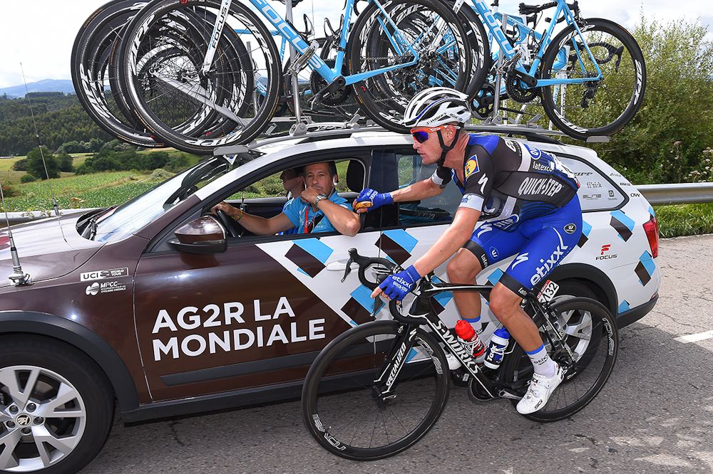 An Etixx rider chats at the AG2R car.