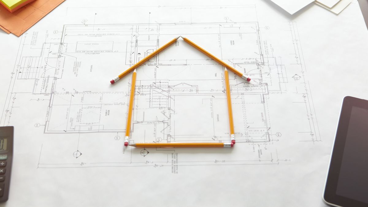 architect plans with house shape constructed using pencils on top of plans