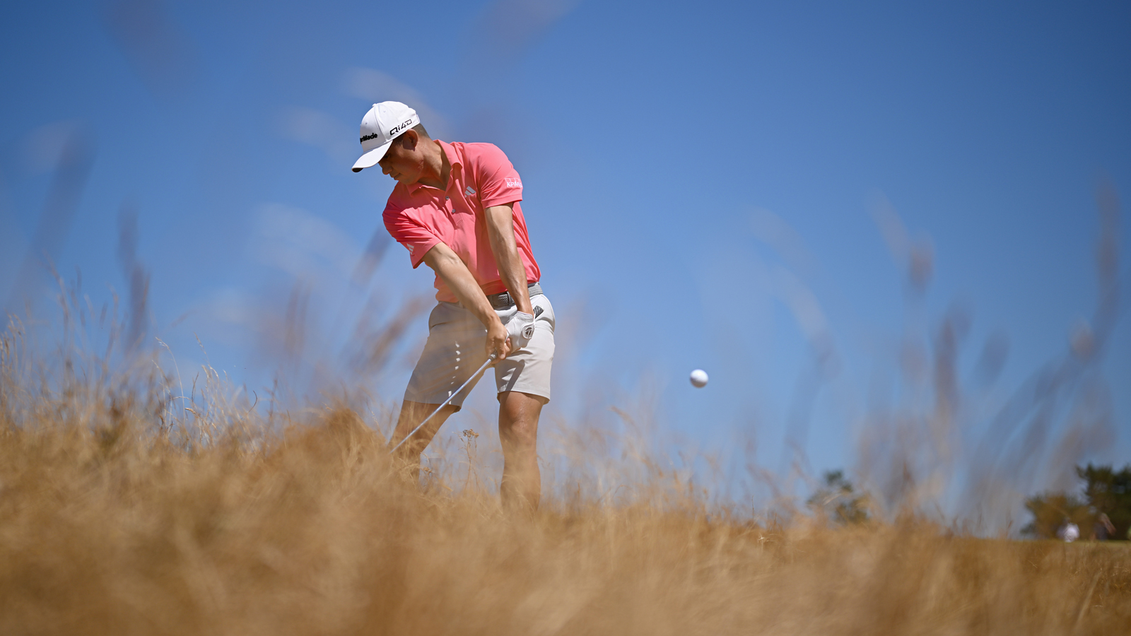 Collin Morikawa hits a shot from the rough