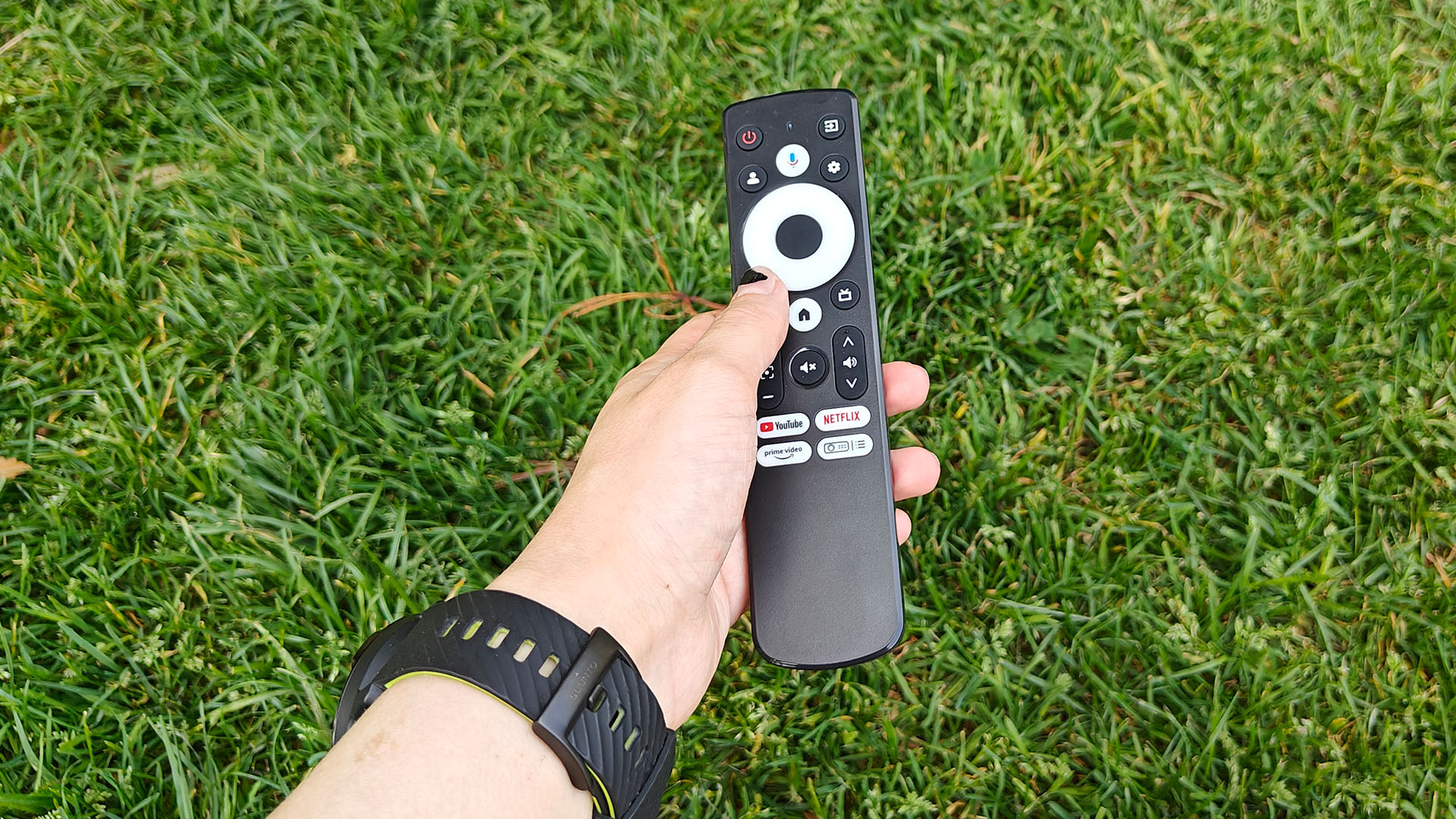 Optoma Photon Go portable UST projector remote control held in hand over grassy lawn