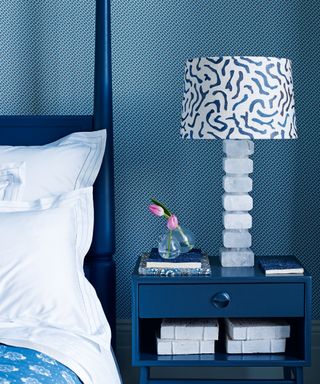 An example of bedroom lighting ideas showing a close up shot of a blue bedroom with a blue bedside table and an ornate blue and white table lamp