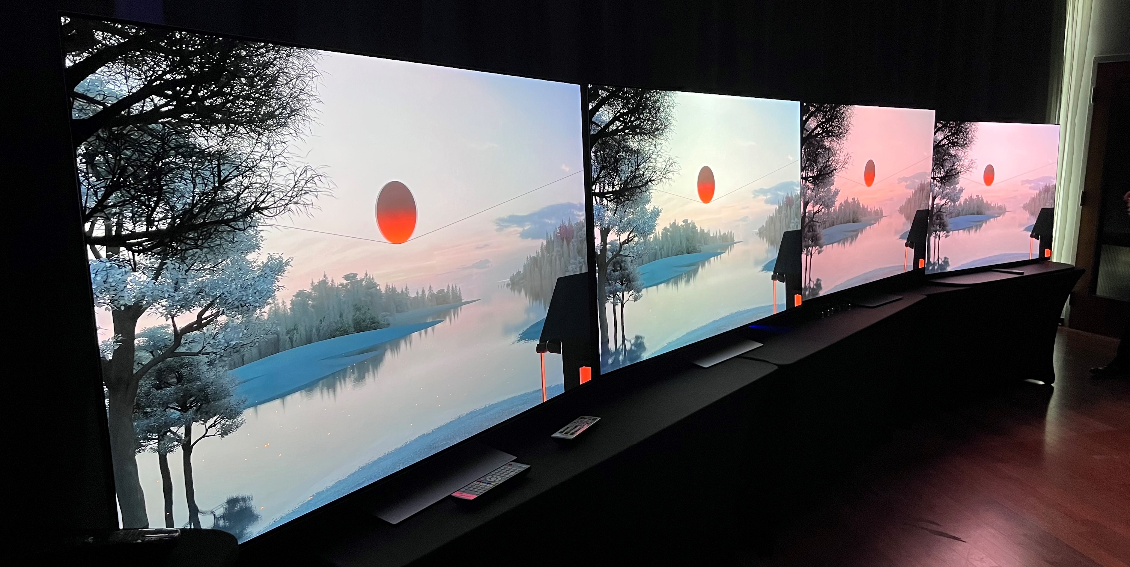 LG G3 OLED-TV på stativ sammen med andre TV-er som viser et landskapsbilde.