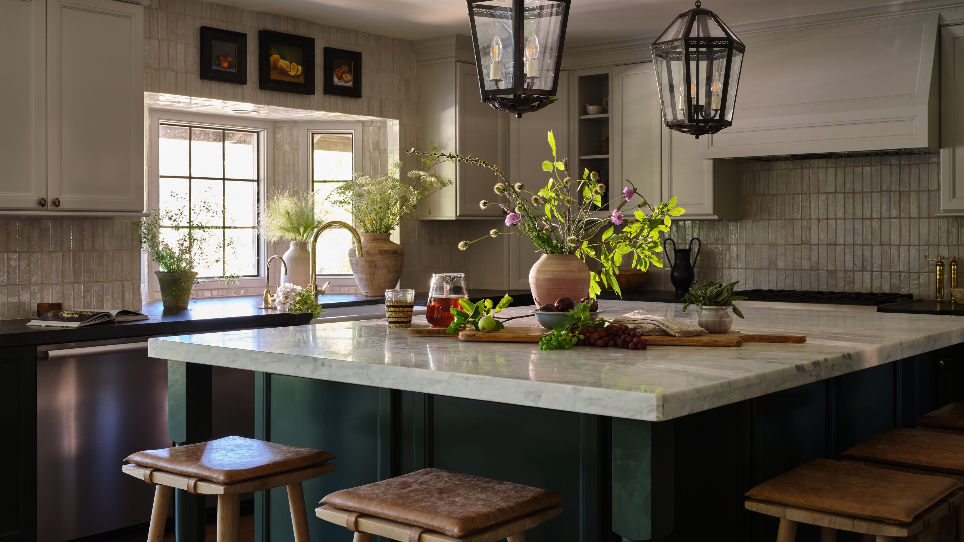 a dark green and neutral two tone kitchen with large painted island and marble counters