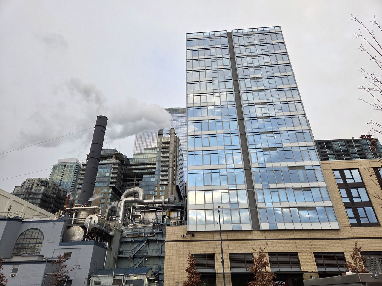 A glass building and smoke stacks