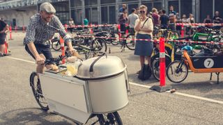 A man rides a hot dog cart built into a cargo bike