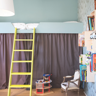 A raised bed in a kids room with yellow ladder and blue walls