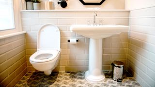 Face on image of white toilet and sink on white metro tiles