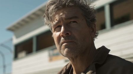 A close up of Kyle Chandler's Hal Jordan sitting at a football stadium in Lanterns episode 2