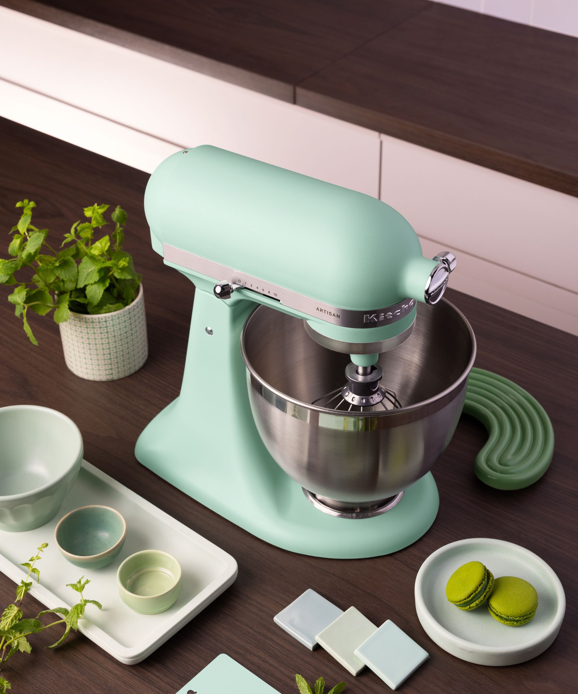 A spearmint blue stand mixer on a dark wooden counter.