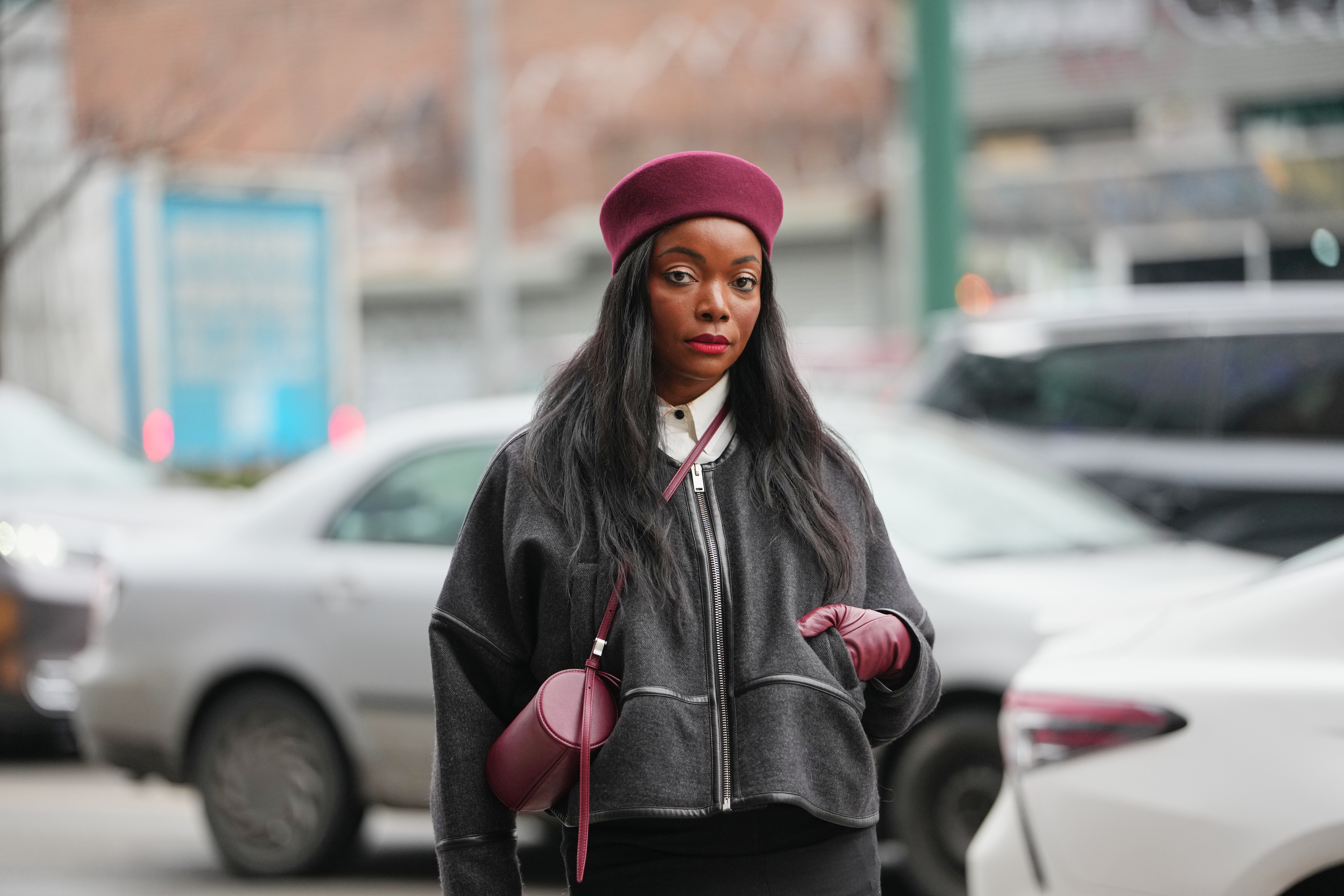 NEW YORK, NEW YORK - FEBRUARY 11: Coco Bassey wears a red burgundy pillbox hat, red lipstick, a red burgundy leather bag, a dark gray zip-up wool jacket, a white shirt, a black skirt, red burgundy leather gloves, outside Proenza Schouler, during New York Fashion Week, on February 11, 2026 in New York City (Photo by Edward Berthelot/Getty Images)