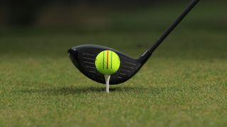 A golfer lining up to hit a ball with their driver