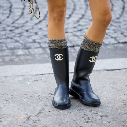  Camille Charriere wears rain boots with logo print, khaki socks outside Chanel during Paris Fashion Week - Womenswear Spring/Summer 2023 : Day Nine on October 04, 2022 in Paris, France. (