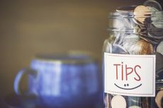 Tip jar with smiley face and a blue mug in the background