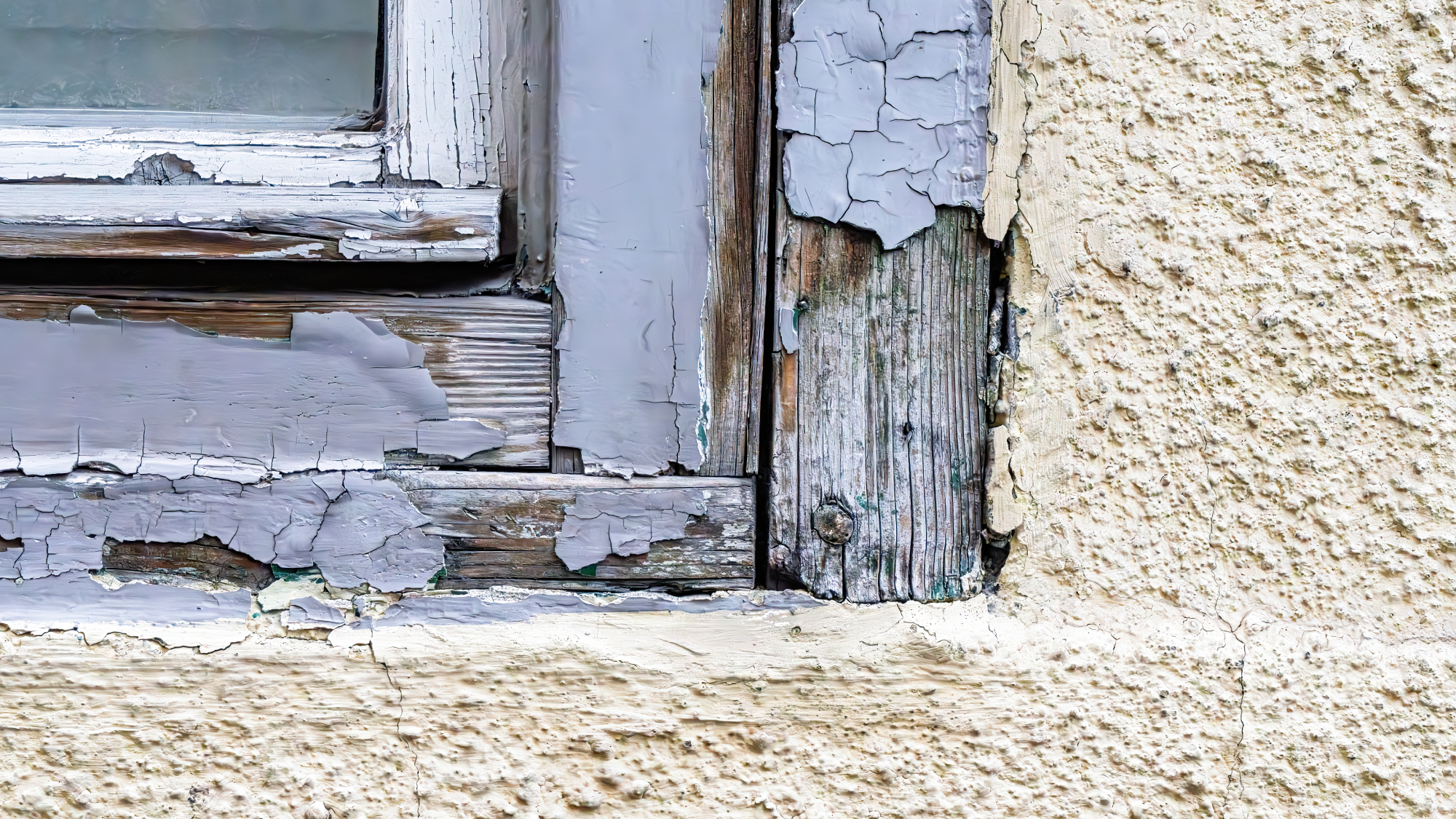 cream exterior wall with painted blue window frame with paint peeling off
