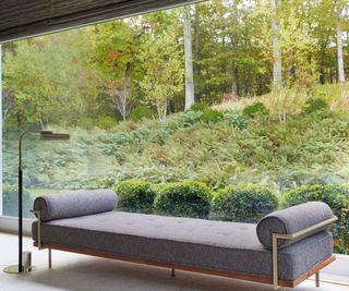 gray couch in room with glass walls and view of wood