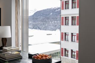 A view through the window from one of the floors, looking out to the snowy mountains and a building next door.