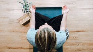 Above shot of woman sat cross-legged on a yoga mat