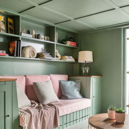 green living room with pink couch and cushions