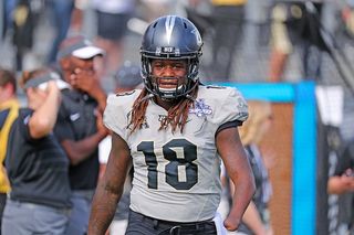 American Football Player In Helmet With Ball In Hands. Fire