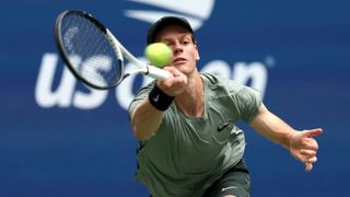 Jannik Sinner plays a forehand return at the US Open 2024 in a khaki t-shirt.